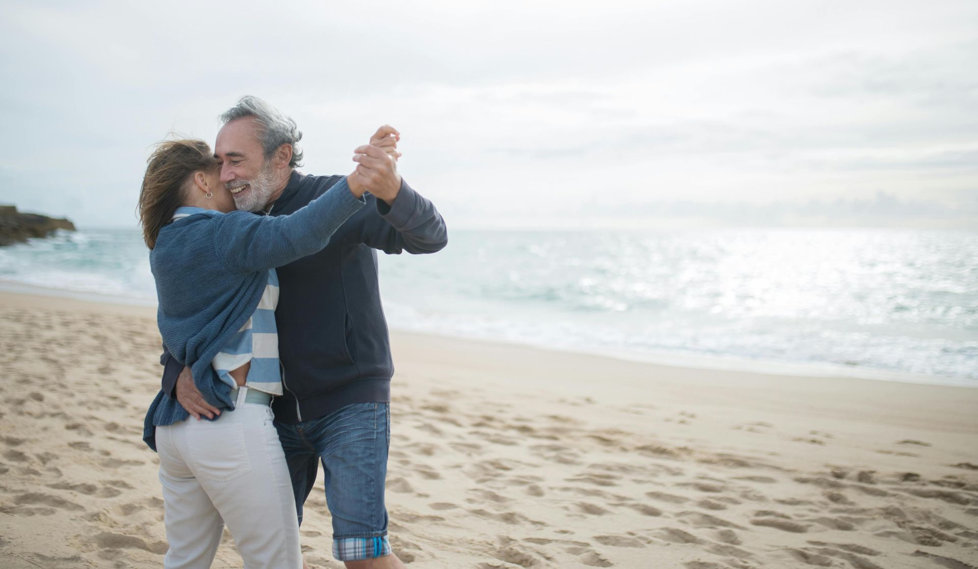 Happy couple dancing on a serene beach in Portugal, embracing love and nature.